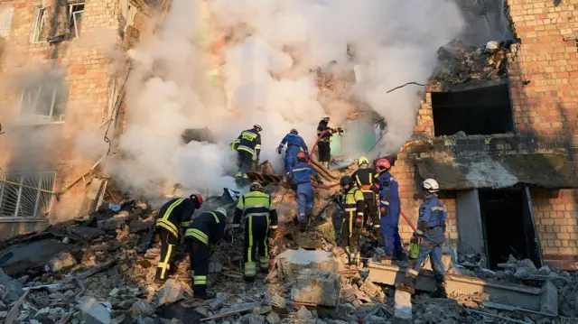 消防员在住宅大楼扑灭火焰,救援人员在俄罗斯弹道导弹袭击后于基辅的瓦砾中搜寻受害者