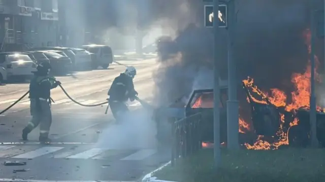 O't o'chiruvchilar Rossiya Belgorodda hujumlardan so'ng yonayotgan mashinani o'chirishmoqda