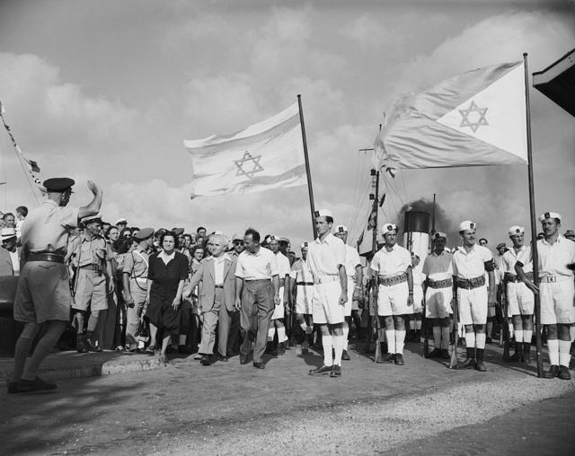 دیوید بن گوریون در حال بدرقه نظامیان بریتانیایی در سال ۱۹۴۸. بعد از خروج بریتانیا از فلسطین، بن‌گوریون تشکیل کشور مستقل اسرائیل را اعلان کرد