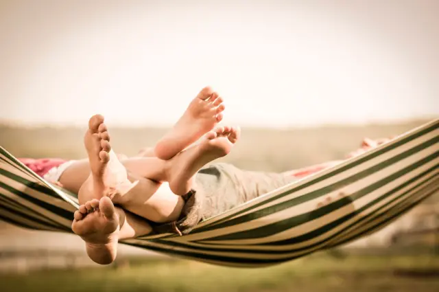 Los pies de una madre y una hija en una hamaca