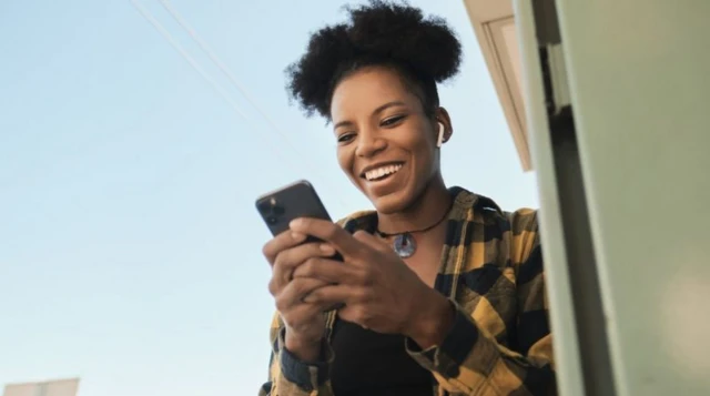 Une femme regarde l'écran de son téléphone et sourit