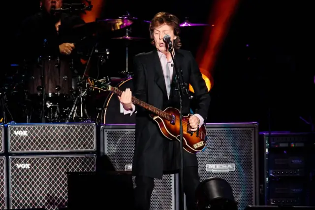 Paul tocando guitarra no palco