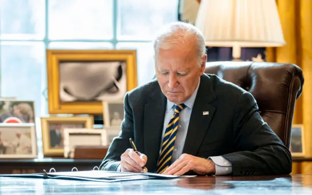 El presidente Biden firma un documento en el Despacho Oval