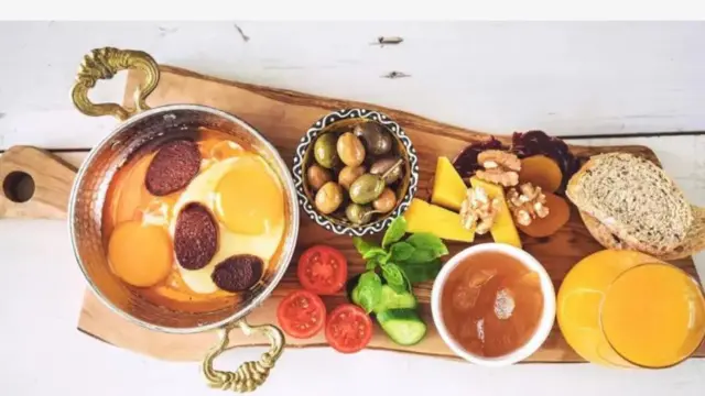 Atẹ fifẹ kan ṣafihan burẹdi gbigbẹ, tomato ti wọn ge, ohun mimu ẹlẹridodo ninu ife ati awọn nnkan jijẹ mi-in.