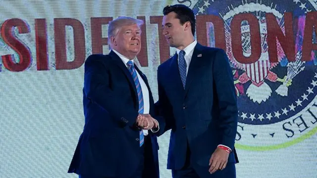 Donald Trump e Charlie Kirk apertam as mãos em palco