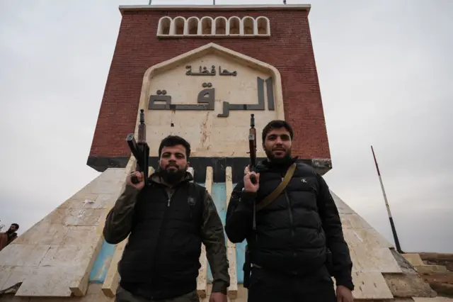 عناصر في الجيش السوري تقف أمام لافتة كُتب عليها "الرقة ترحب بكم" بعد انسحاب قوات سوريا الديمقراطية من قرية في ريف الرقة في 17 يناير/ كانون الثاني 2026