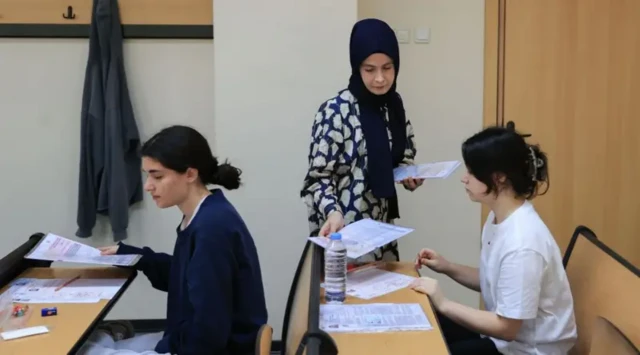 Sınav kağıtlarını öğrencilere dağıtan bir gözetmen