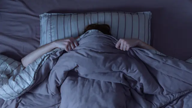 লেপের তলায় মুখ ঢাকা এক ব্যক্তি