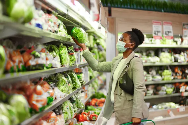 Une femme dans une épicerie choisissant et parcourant l’allée des produits frais