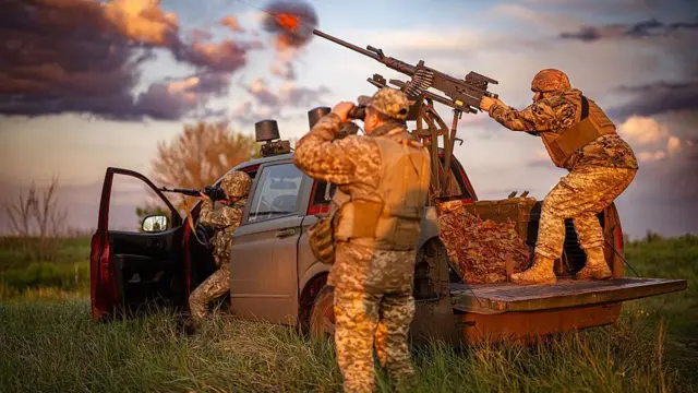 Група військових на пікапі, один прицілився з кулемета, інший дивиться у бінокль 