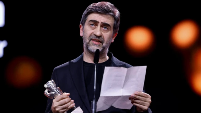 Emin Alper elinde bir kağıttan ödül törenindeki konuşmasını yapıyor. Diğer elinde ödül var.