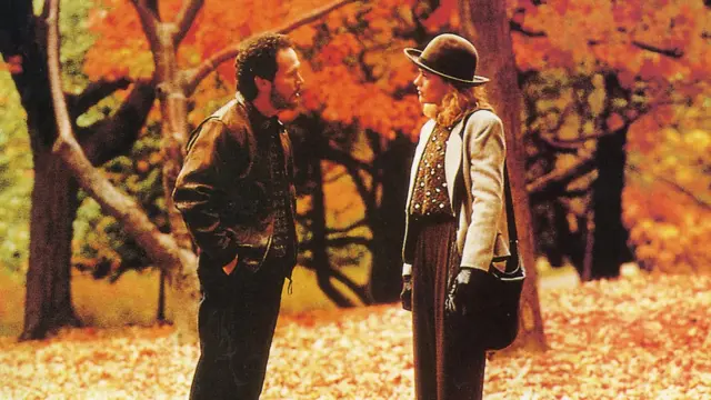 Мушкарац и девојка са шеширом у природи окружени лишћем 