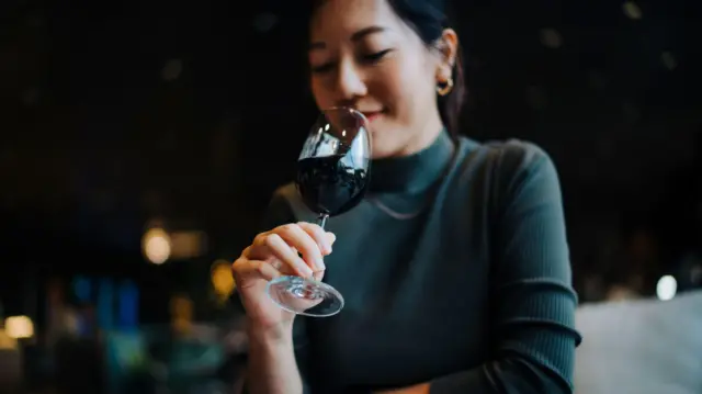वाइन की ख़ुशबू लेती एक महिला