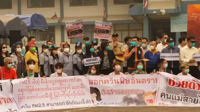 Warga setempat menggelar demonstrasi dengan menggunakan masker dan mendesak agar pemerintah bertindak dengan slogan seperti “Selamatkan Mae Sai”