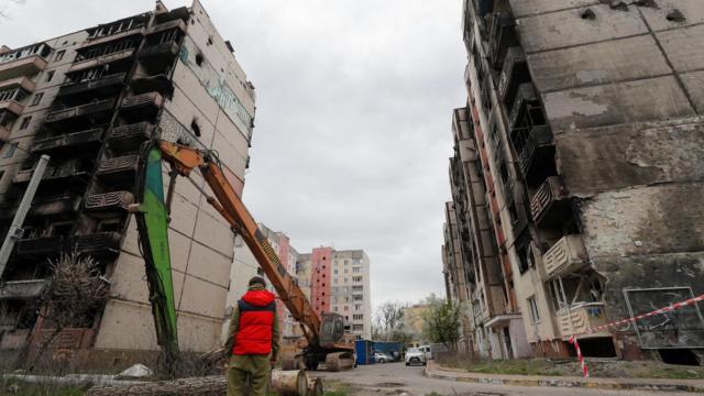 Homem observa prédios parcialmente queimados e destruídos por bombardeios