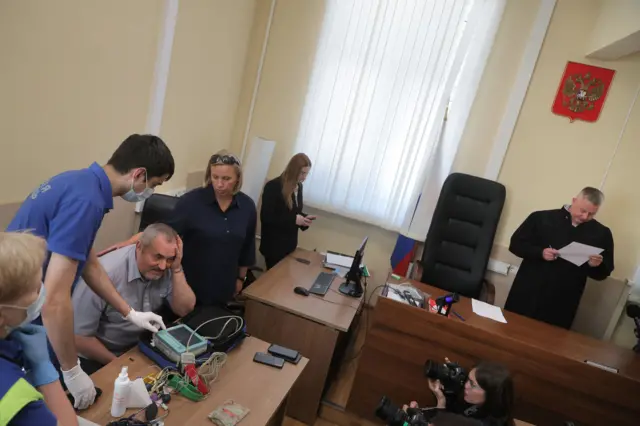 Зал заседания суда, Надеждин слушает решение, схватившись за голову, слева от него врачи «скорой помощи» 