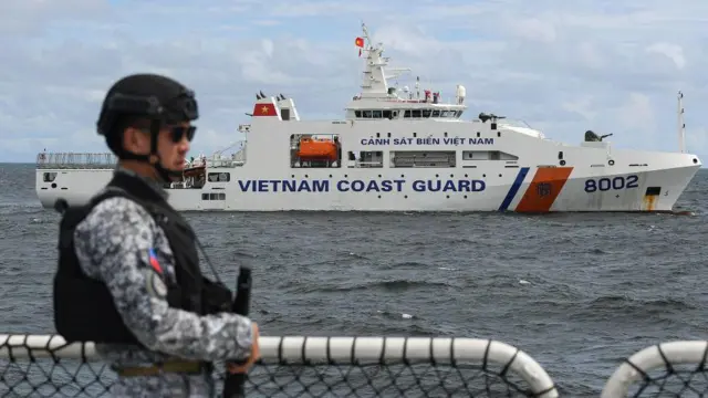 A member of the Philippine Coast Guard personnel stands guard aboard the Gabriela Silang ship as a Vietnamese Coast Guard ship sails past during a joint maritime exercise off Bataan in the disputed South China Sea on August 9, 2024. 