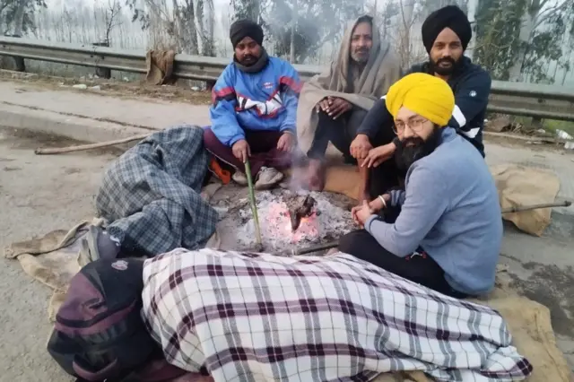 ਕਿਸਾਨ ਅੰਦੋਲਨ ਦੌਰਾਨ ਵੀਰਵਾਰ ਦੀ ਸਵੇਰ ਕੁਝ ਨੌਜਵਾਨ ਅੱਗ ਸੇਕਦੇ ਹੋਏ ਜਦਕਿ ਦੋ ਜਣੇ ਖੇਸ ਲਈ ਕੋਲ ਹੀ ਨਿੱਘ ਵਿੱਚ ਸੁੱਤੇ ਹੋਏ ਹਨ