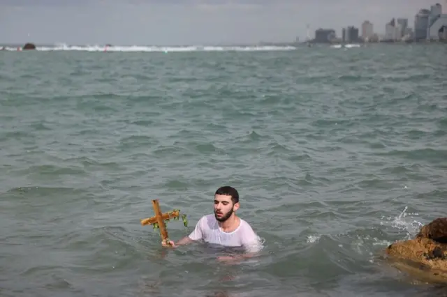 Хришц́ански верник из грчко-православне цркве Арханђела Михаила држи крст након што га је извукао из Средоземног мора током прославе Богојављања у Старој луци Јафа у Тел Авиву, Израел, 19. јануара 2026. Годишњи фестивал обележава долазак Три мудраца у Витлејем да се поклоне новорођеном Христу према хришц́анској традицији