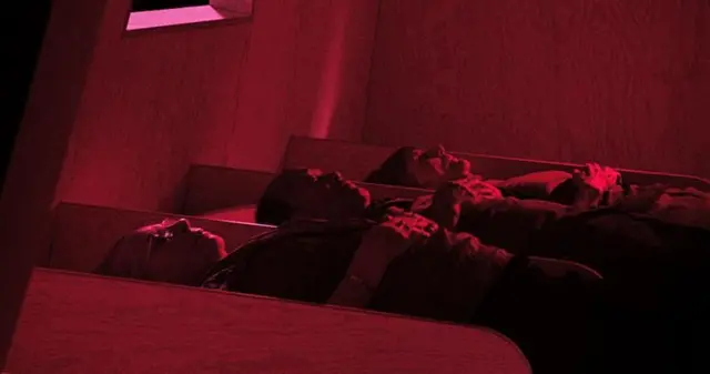 Imagem de três pessoas deitadas sob luz rosa