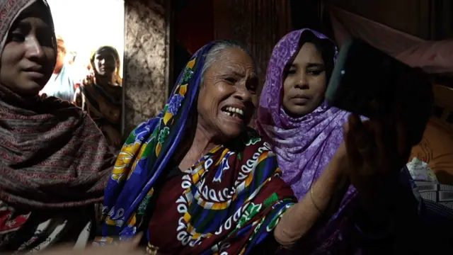 Sakina Begum parle à sa famille sur un téléphone portable sous le regard des habitants qui lui ont offert un abri.