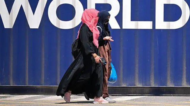 9 Nisan 2026’da Islamabad’daki Kırmızı Bölge’de yetkililerin bir yolu kapatmasının ardından kadınlar bir nakliye konteynerinin yanından yürüyor. Yetkililer, ABD ile İran arasında Islamabad’da yapılması planlanan görüşmeler öncesinde Pakistan’ın başkentte 9 Nisan’dan itibaren iki günlük resmi tatil ilan ettiğini söyledi.<p>