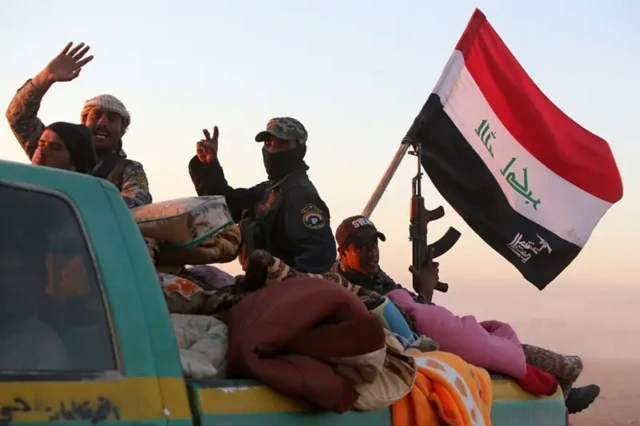 اعضای حشد شعبی عراق در پشت یک وانت در حاشیه شهر الدور در عراق نشسته‌اند، ۶ مارس ۲۰۱۵
این تصویر در جریان عملیات نظامی برای بازپس‌گیری منطقه تکریت از داعش گرفته شده است
