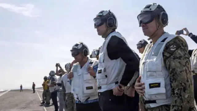 استیو ویتکاف به همراه جرد کوشنر بر عرشه ناو هواپیمابر «یو‌اس‌اس آبراهام لینکلن» در حالی که در کنار شمار دیگری واسکت سفید و عینک‌های خاص نظامی به چشم دارند.
