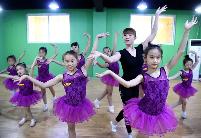 Seorang wanita mengajarkan latihan dasar kepada anak-anak di sebuah pusat pelatihan tari anak pada tanggal 26 Juni 2016 di Bozhou, Provinsi Anhui, China.
