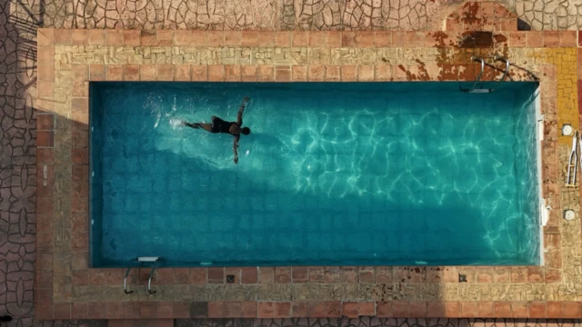 A swimming pool wit a young girl in it. She is swimming