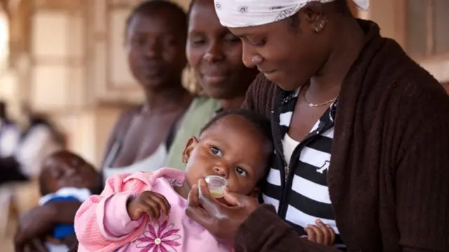Мать дает ребенку противомалярийный препарат