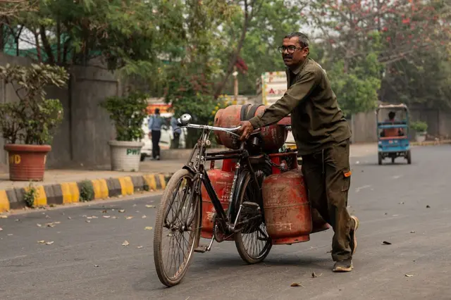 दिल्लीतल्या एका गॅस डेपोजवळ एक माणूस एलपीजी (लिक्विड पेट्रोलियम गॅस) सिलिंडर सायकलवर घेऊन जातो आहे. 