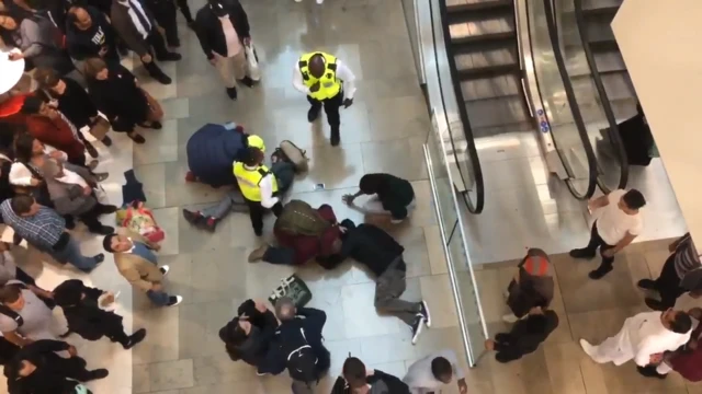 Imagem tomada instantes depois de homem (deitado à direita, de capuz) cair sobre Grace Spence Green (deitada à esq.) no shopping Westfield, em Londres
