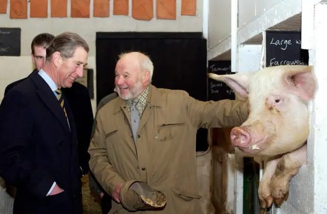 King Charles III posed with pig farmer Peter Hart and "Sally The Sow", during a visit to Warriner School Organic Farm, 31 January 2003.