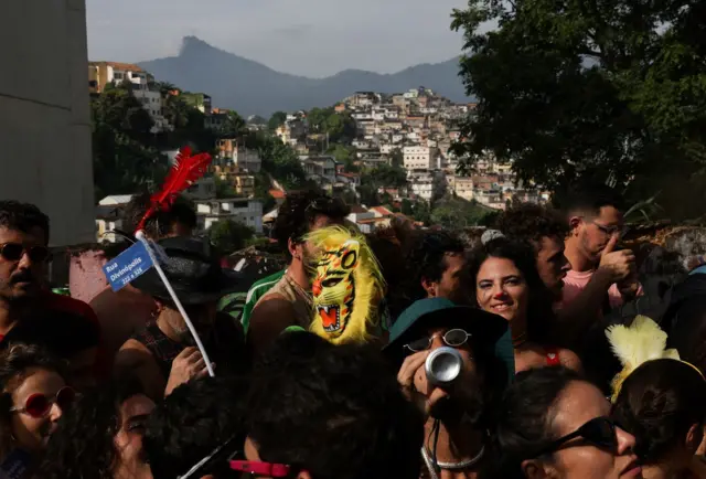 Foliões e paisagem do Rio atrás, com Corcovado e Santa Teresa