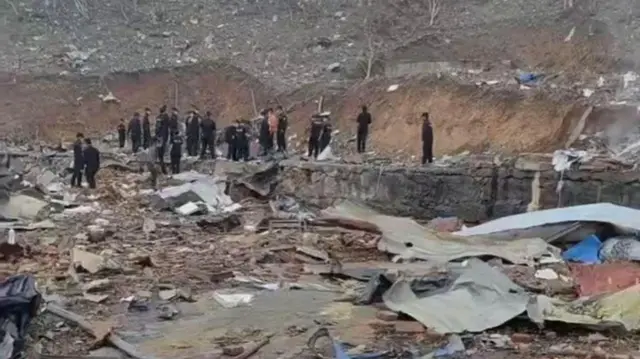 ပေါက်ကွဲမှုကြောင့် ပျက်စီးသွားတဲ့ အပိုင်းအစတွေကို "ဝ"တပ်ဖွဲ့ဝင်တွေ ရှင်းလင်းနေတဲ့မြင်ကွင်း