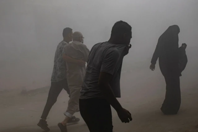 أشخاص يسيرون وسط دخان كثيف ناجم عن انفجار في مدينة غزة - أيلول سبتمبر