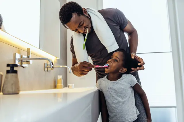 Père qui brosse les dents de sa fille