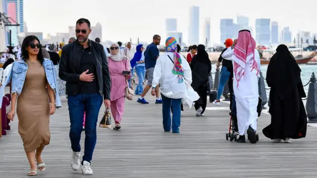 عدد من الأشخاص يمشون بجانب البحر في إحدى الدول العربية.