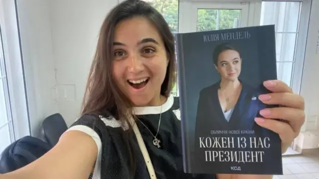 Юлія Мендель тримає в руці книгу "Кожен з нас - Президент"