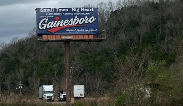Una valla publicitaria frente a una carretera que dice: "Pueblo pequeño, gran corazón, aquí no hay lugar para ideas desagradables. Gainesboro: donde todos son bienvenidos".