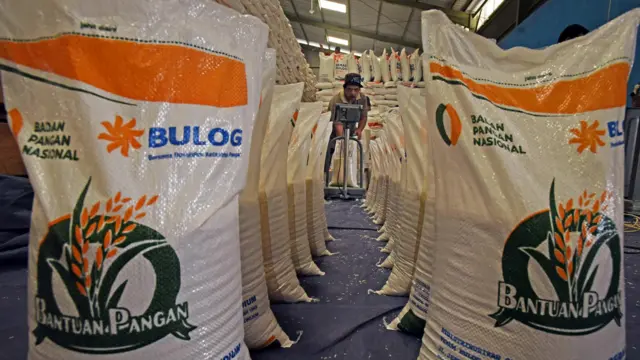 Pekerja menjahit karung berisi beras paket bantuan sosial pangan ukuran 10 kilogram di gudang Bulog Serang, Banten, Jumat (01/03).