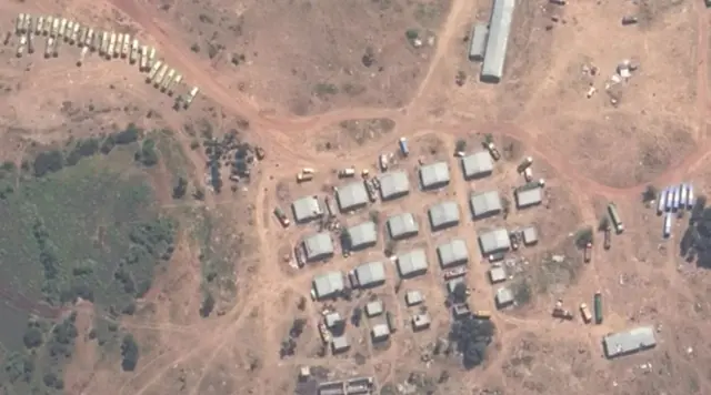 ኣውቶቡሳትን ወተሃደራውያን ተሽከርከርትን ኣብ ጥቓ ጽርግያ ዓዲ ጎሹ ኣብ ሓደ ሓደ ህንጻታት ደው ኢለን ይረኣያ