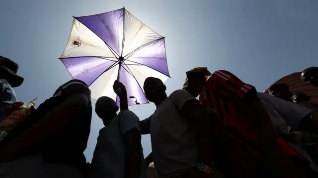 Abantu bitwikiriye umutaka bari ku murongo