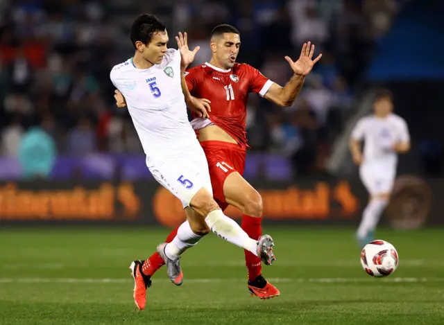 اللاعب السوري بابلو صباغ (يمين) مع اللاعب الأوزبكستاني رستمجون آشورماتوف خلال مبارة جمعت المنتخبين في كأس آسيا