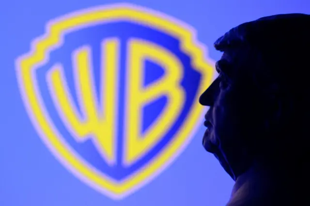 Miniatura em impressão 3D do rosto do presidente dos EUA, Donald Trump, posicionada em frente ao logotipo da Warner Bros