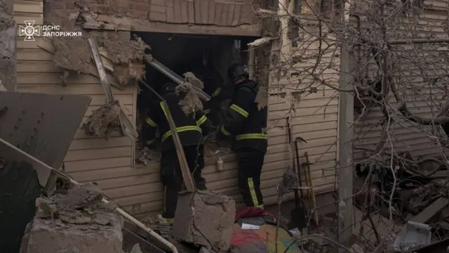 Зруйнований будинок, у який заглядають рятувлаьники