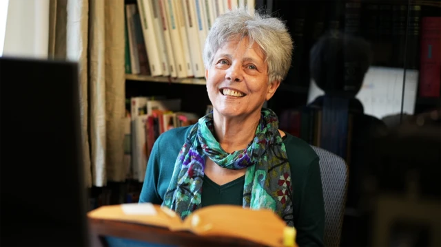 Kitabın yazarlarından Osmanlı mutfak kültürü tarihçisi Mary Işın çalışma ortamında. Bilgisayarı başında, kitaplarının arasında gülümsüyor. Boynuna koyu yeşil kazağıyla uyumlu yeşilli mavili bir eşarp bağlamış. 