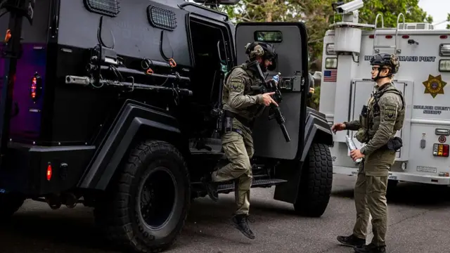 Dos policias se bajan de vehículos blindados en el lugar de los hechos