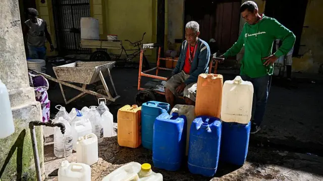 Люди стоят в очереди, чтобы наполнить свои емкости водой в Гаване во время общенационального отключения электроэнергии 22 марта